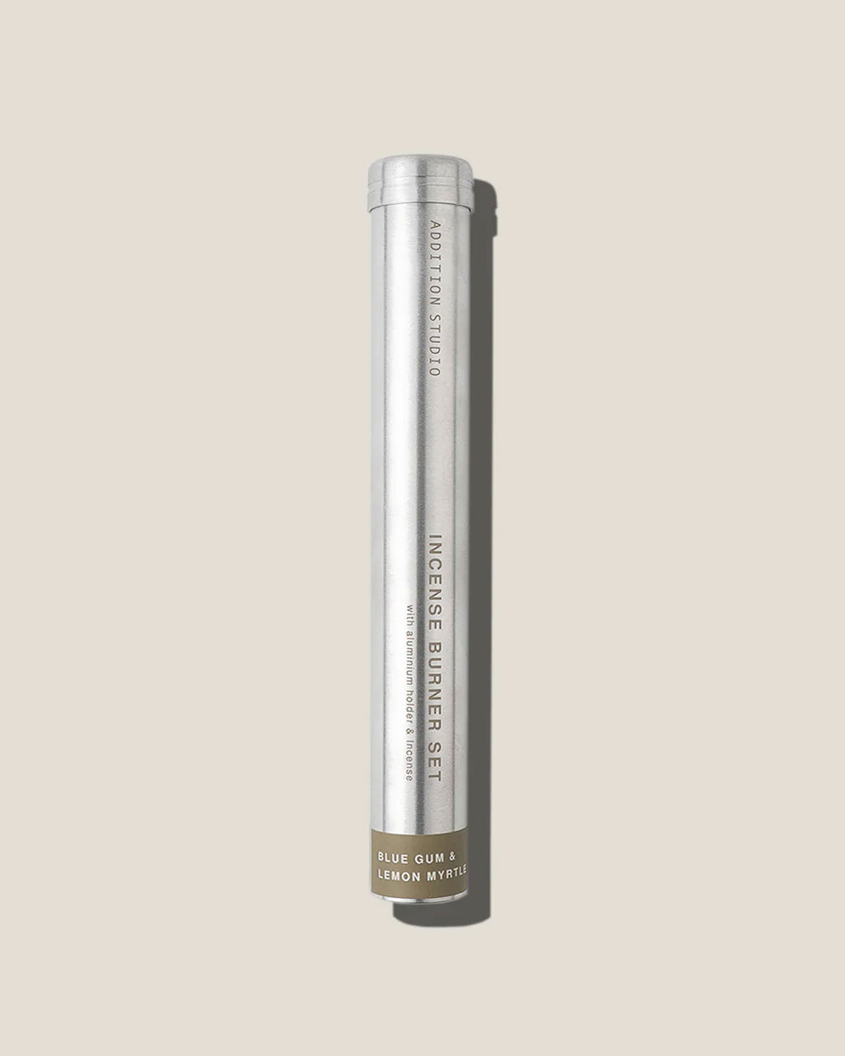 A tall, slim aluminium canister with printed lettering reads Addition Studio Incense Burner Set, Blue gum and lemon myrtle on an off-white background.
