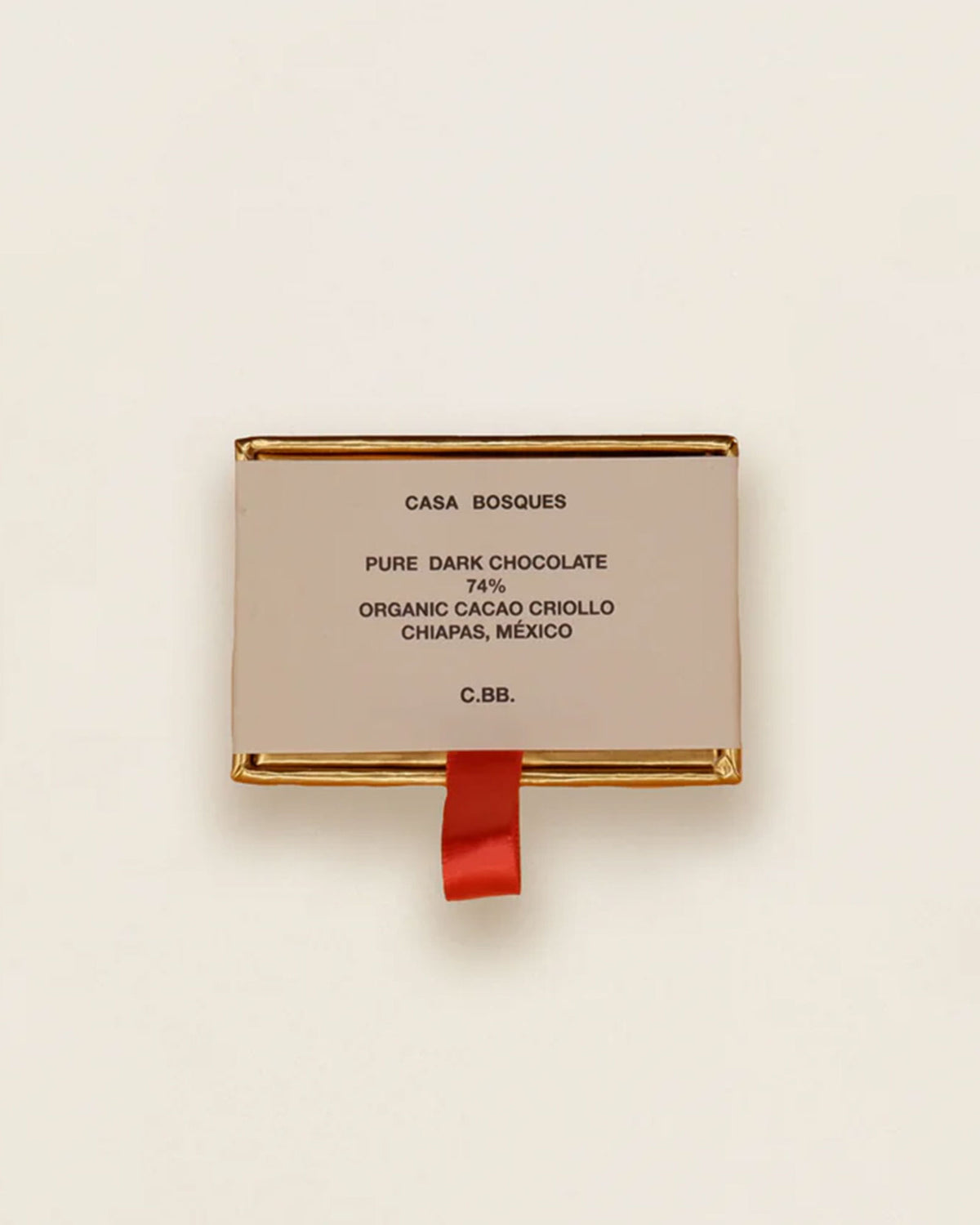 A single rectangular package of Casa Bosques Chocolate Dominoes on a clean off-white background. The package is a light beige/cream color with gold metallic borders and a small red ribbon hanging from the bottom.