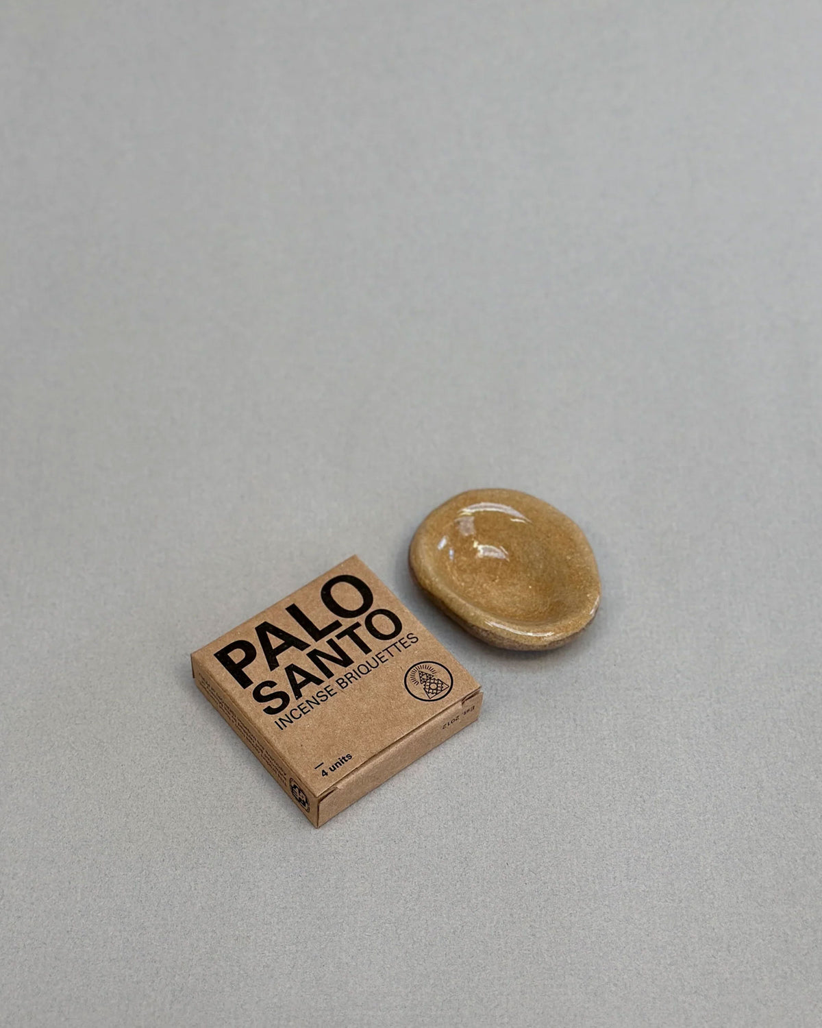A small tan ceramic dish and a small cardboard packaging box labeled &
