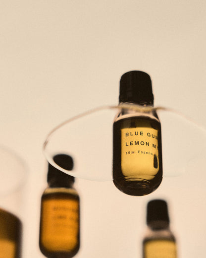 A photograph taken from underneath a clear glass surface that shows three essential oil bottles sitting on the surface. 