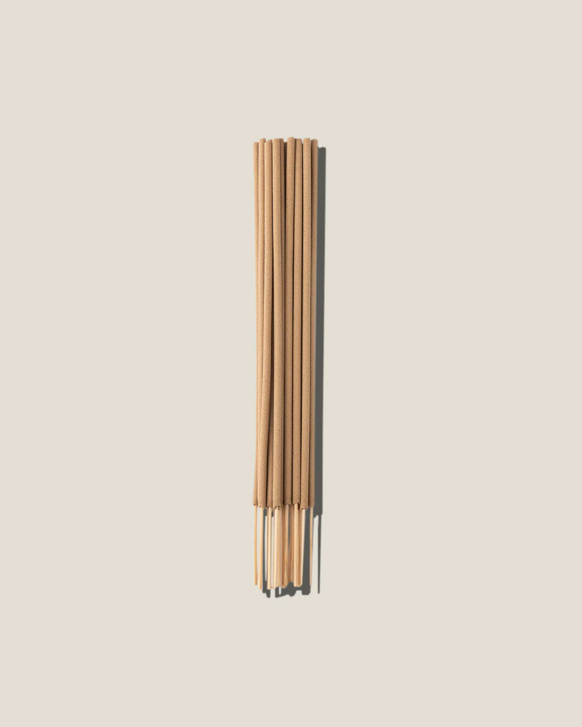 A bunch of light brown incense sticks centred on an off-white background. 