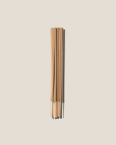 A bunch of light brown incense sticks centred on an off-white background. 