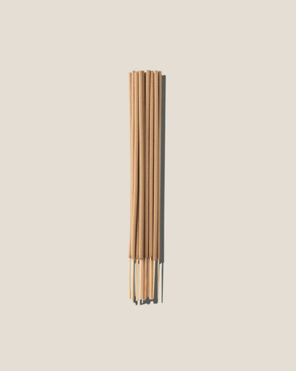 A bunch of light brown incense sticks centred on an off-white background. 