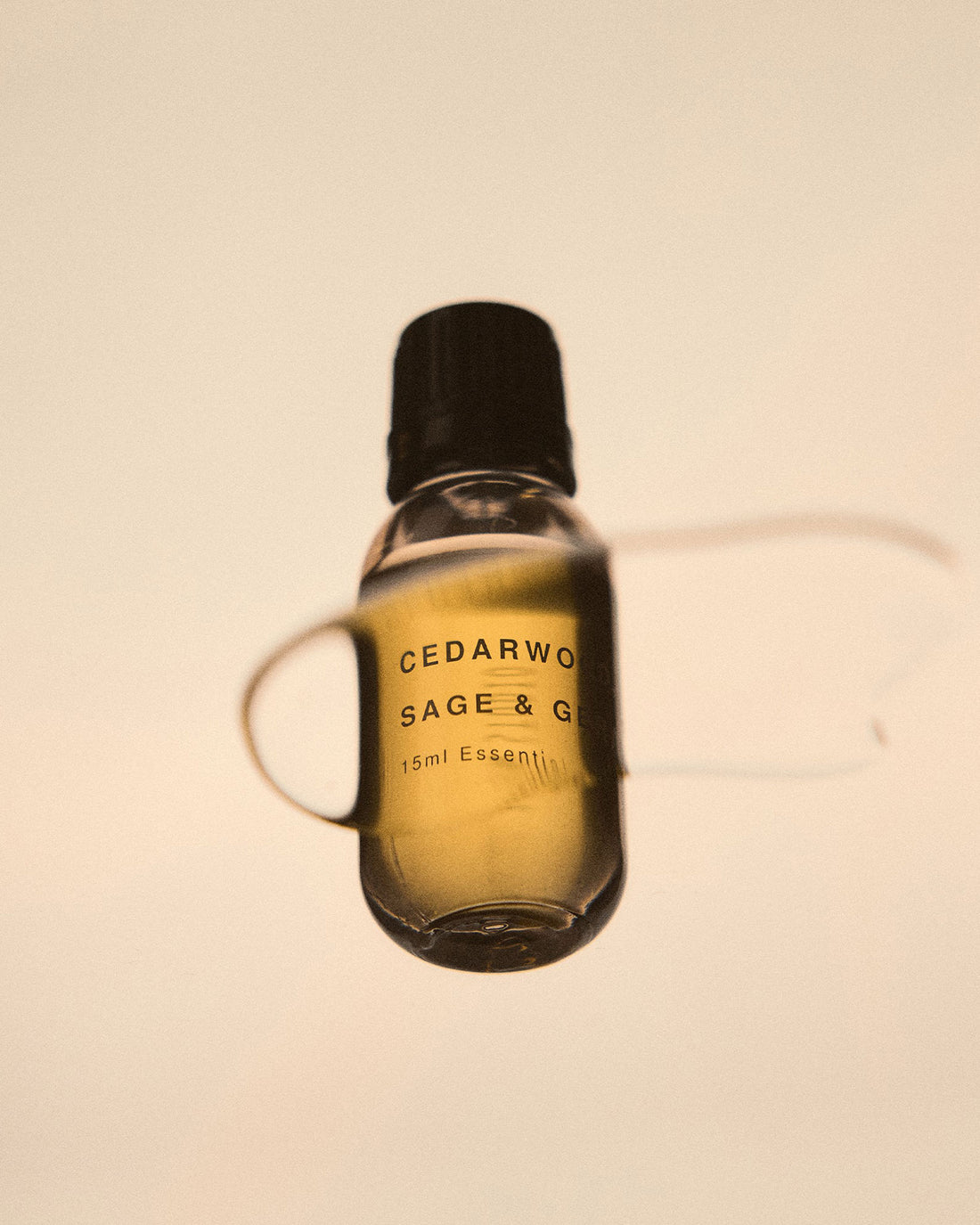 A photograph taken from underneath a clear glass surface that shows an Addition Studio essential oil bottle sitting on the surface. 