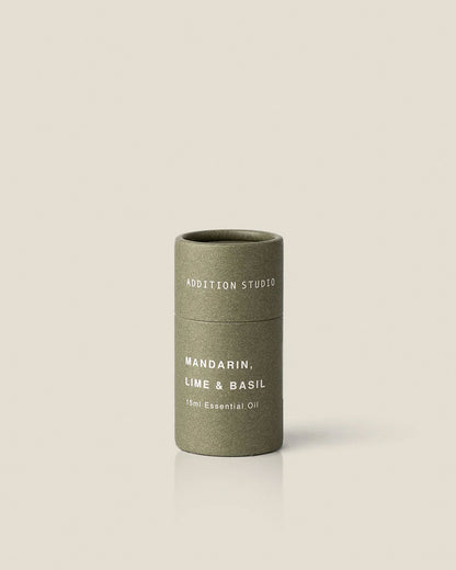 A small olive green coloured cardboard canister with white printed text which reads Addition Studio Mandarin, Lime and Basil 15ml Essential Oil on an off-white background. 