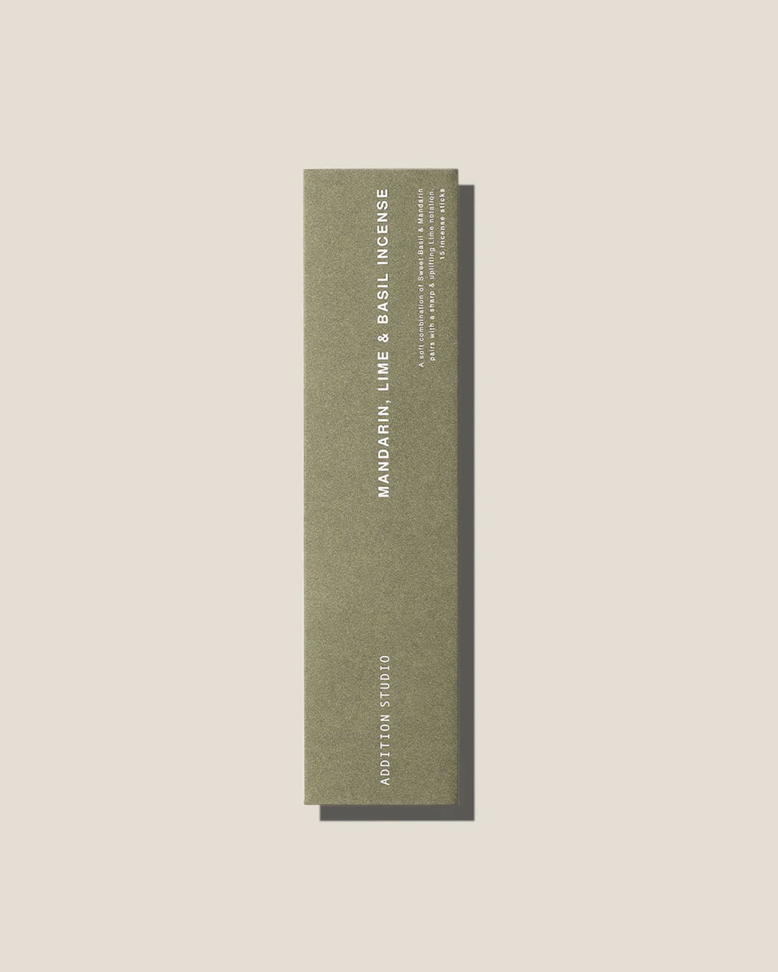 An olive-green long, slim rectangular cardboard package with white type which reads Addition Studio MANDARIN, LIME AND BASIL INCENSE, set on an off-white background.