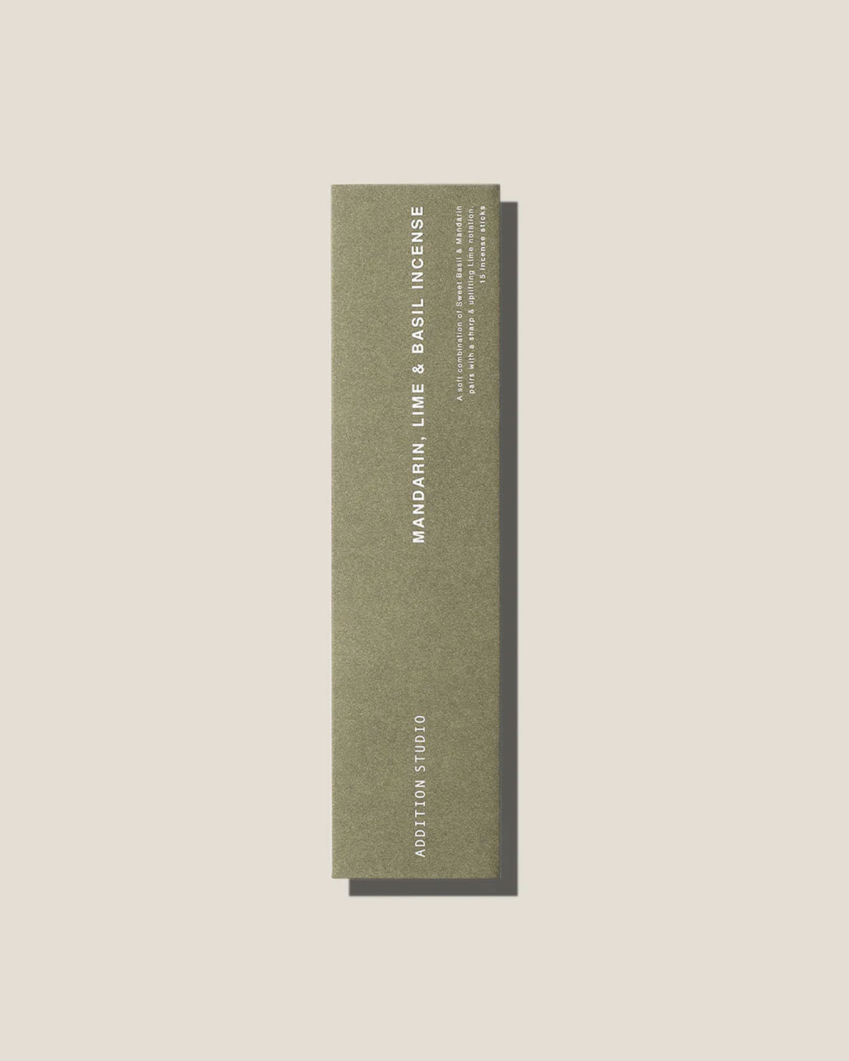 An olive-green long, slim rectangular cardboard package with white type which reads Addition Studio MANDARIN, LIME AND BASIL INCENSE, set on an off-white background.