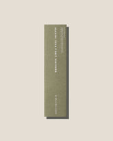 An olive-green long, slim rectangular cardboard package with white type which reads Addition Studio MANDARIN, LIME AND BASIL INCENSE, set on an off-white background.