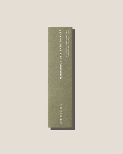 An olive-green long, slim rectangular cardboard package with white type which reads Addition Studio MANDARIN, LIME AND BASIL INCENSE, set on an off-white background.
