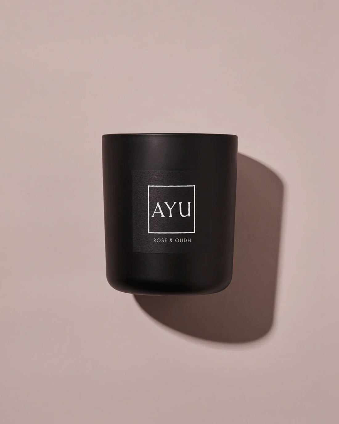 A matte black candle jar with a minimalist black label with white lettering reading &