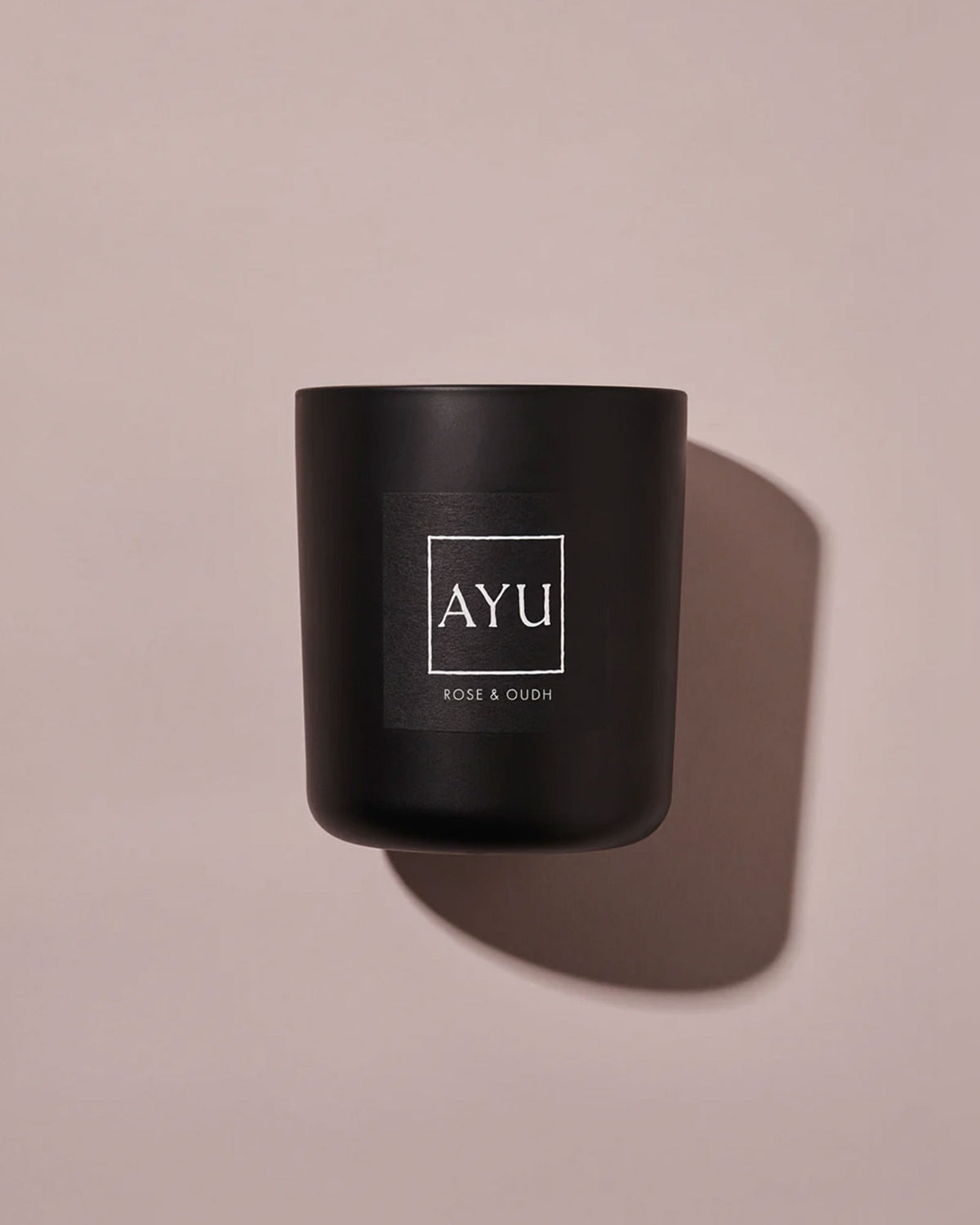 A matte black candle jar with a minimalist black label with white lettering reading &