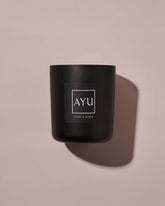 A matte black candle jar with a minimalist black label with white lettering reading &