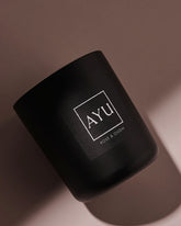 A matte black candle jar with a minimalist black label with white lettering reading &