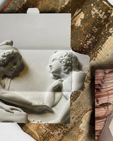 The inside packaging of a Casa Bosques chocolate bar. A cardboard package with an image of a marble statue.