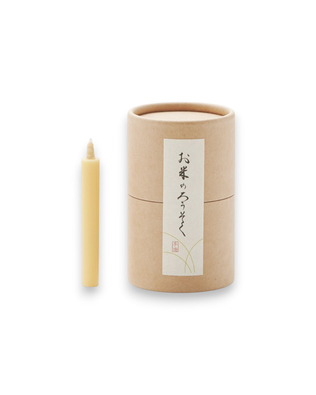 Product shot of one natural-coloured tapered candle alongside a cardboard canister, sealed with a label picturing Japanese characters. 