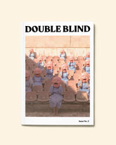 The cover of issue three Double Blind Magazine on a pale-yellow background featuring a computer generated image of several people with the same enlarged, distorted face and the same blue long-sleeved dress randomly sitting along chairs similar to stadium chairs.