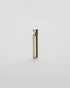 A minimalist, modern geometric bottle opener with a gold brushed metal finish, standing upright on a seamless light grey background.