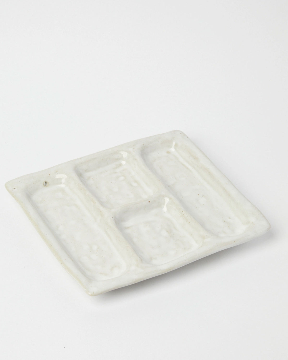 Product shot of a white ceramic platter designed with 4 recessed compartments.