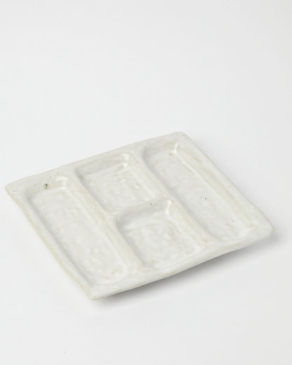 Product shot of a white ceramic platter designed with 4 recessed compartments.