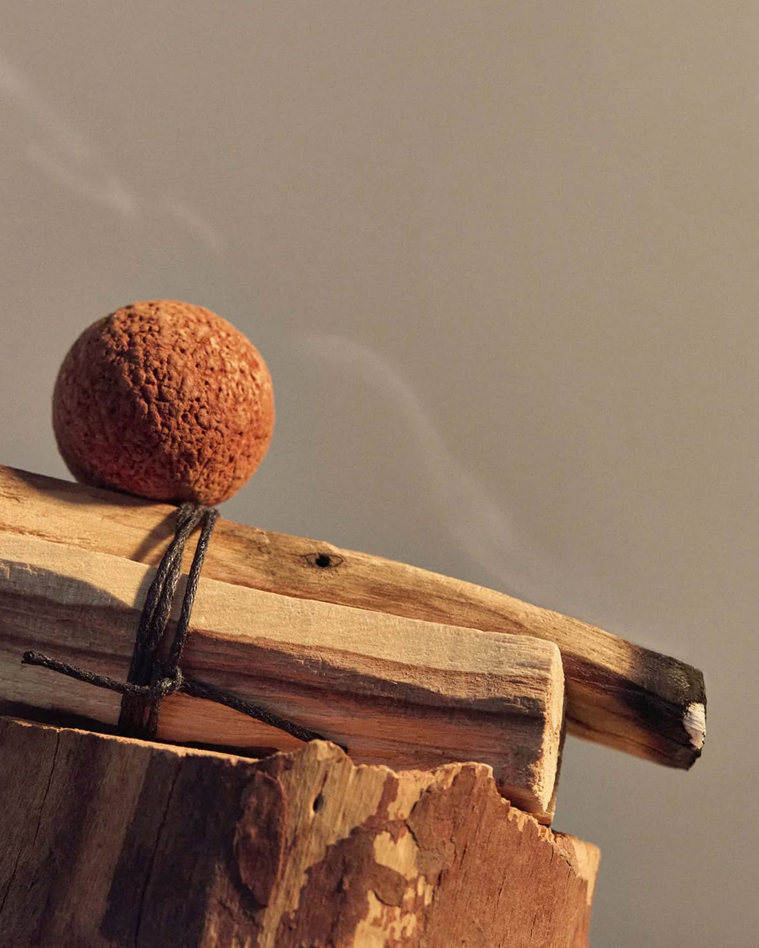 A bundle of 2 small wood pieces, one is gently smouldering. 