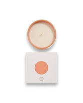 Birdseye view of a round unlit candle next to its square box that features a white lid with a peach coloured circle corresponding to the same colour of the candle container. The box reads Bougie Perfumee 280g, set on an all white background.