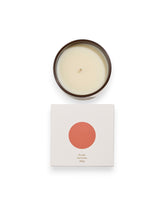 Birdseye view of a round unlit candle next to its square box that features a white lid with an orange coloured circle. The box reads Bougie Perfumee 280g, set on an all white background.
