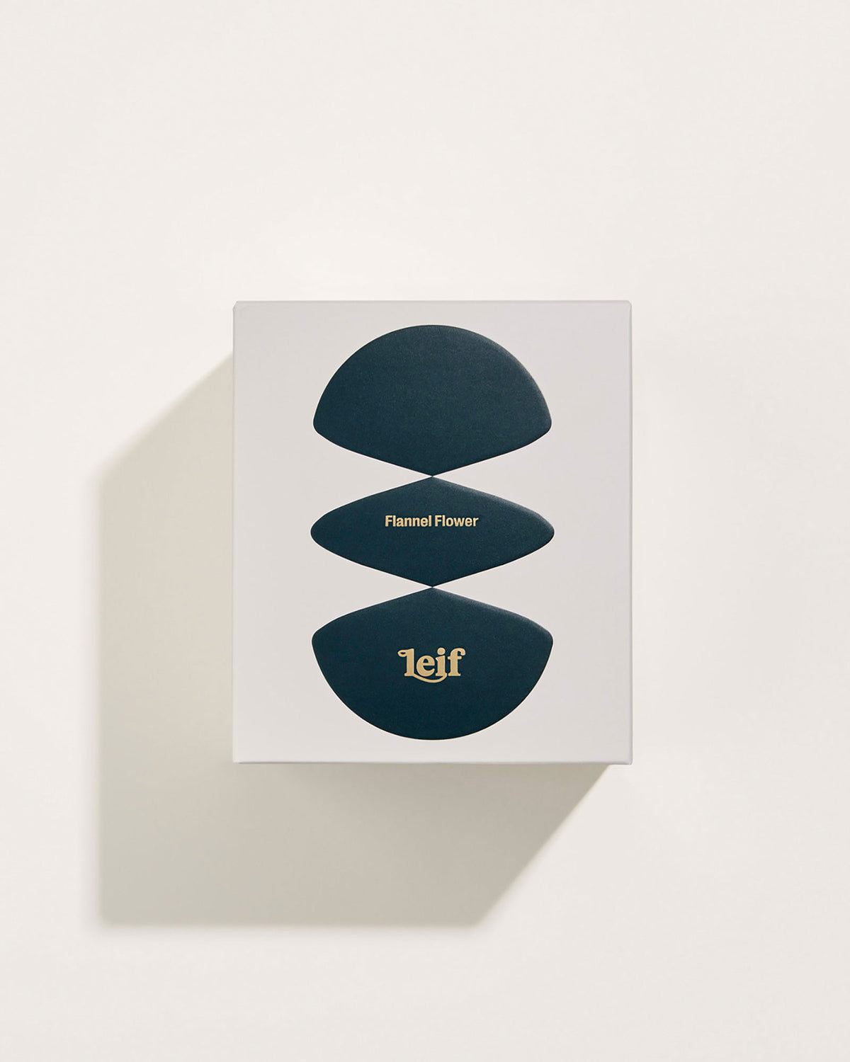A square white box with a black abstract pattern with gold foil lettering which reads Flannel Flower Leif. Set on a white background.
