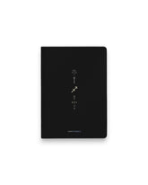 A black hardcover notebook featuring the Sagittarius zodiac sign and its chart symbols printed in metallic on the front cover, set against a clean white background.