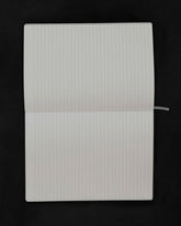 An open lined notebook with blank white pages, photographed from above against a solid black background.