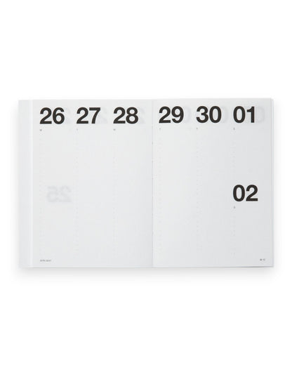 A white paper calendar page spread open, showing the days of the week with black printed numbers. The page is photographed against a clean white background.