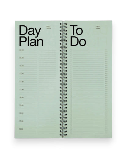 An open spread of a tall, rectangular ring-bound day planner with light green pages set on a solid white background. 