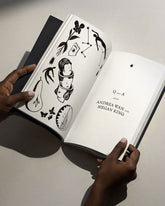 An open spread of the Poesis Visions and Verses Guidebook held open by two hands. Several unrelated hand drawn illustrations are on the left page, on the right is a title page hat reads Q and A with Andrea Wan and Megan King. White background.