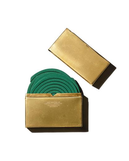 Two brass metal box halves on a white background, one containing several green mosquito coils and the other is empty, placed to show how it becomes the lid of the box. Set on a white background.
