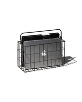 A black rectangular wire basket with handle holding a mac lap book and a black folder. Set on a white background. 