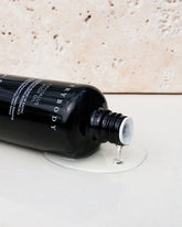 A black, cylindrical, glass bottle of Sodashis&
