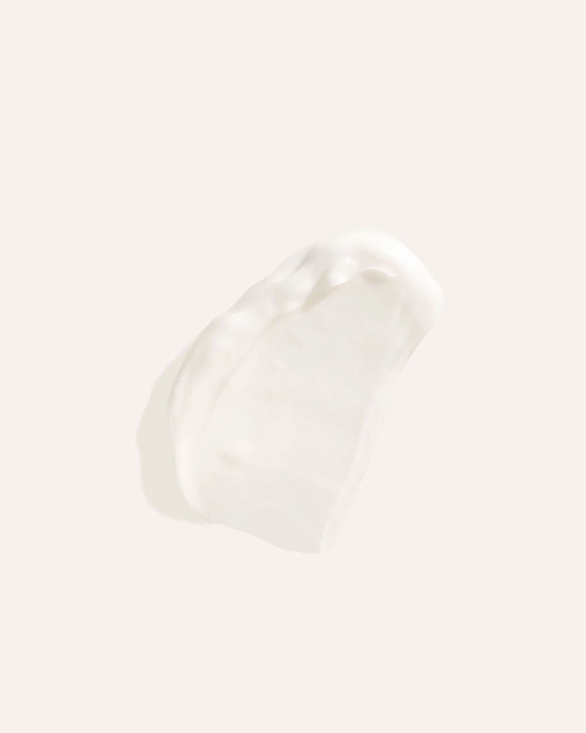 A smear of white cream on an off-white background.