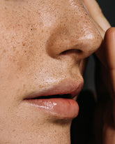 Close-up of a woman touching her face.