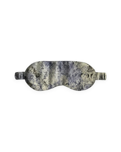A silk eye mask with a marbled pattern in cream, beige, and dark purple, shown against a plain white background.