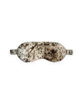 A silk eye mask with a marbled pattern in cream, beige, and dark brown, shown against a plain white background.