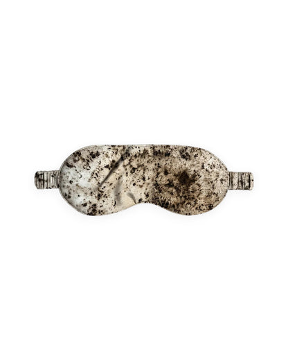 A silk eye mask with a marbled pattern in cream, beige, and dark brown, shown against a plain white background.