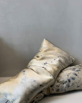 Two weighted eye pillows with mottled blue and beige abstract patterned silk slips.