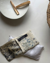On a concrete surface next to a ceramic bowl with two sticks of Palo Santo wood, a Solty&