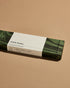 A closed green marbled box of Subtle Bodies Taiwanese Hinoki Incense with a white wrap around label. Set on a light orange background. 