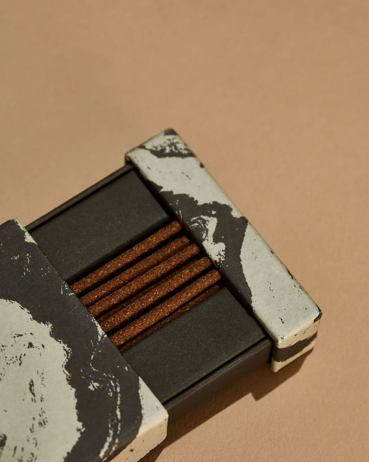 A partially opened box of Subtle Bodies Peruvian Palo Santo Incense on a light orange background. 