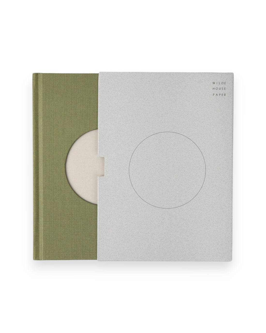 A Wilde House Paper hardcover journal, moss-coloured with a large circular cutout in the center is semi exposed from its grey coloured case.
