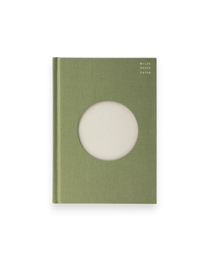 A Wilde House Paper hardcover journal, moss-coloured with a large circular cutout in the center.